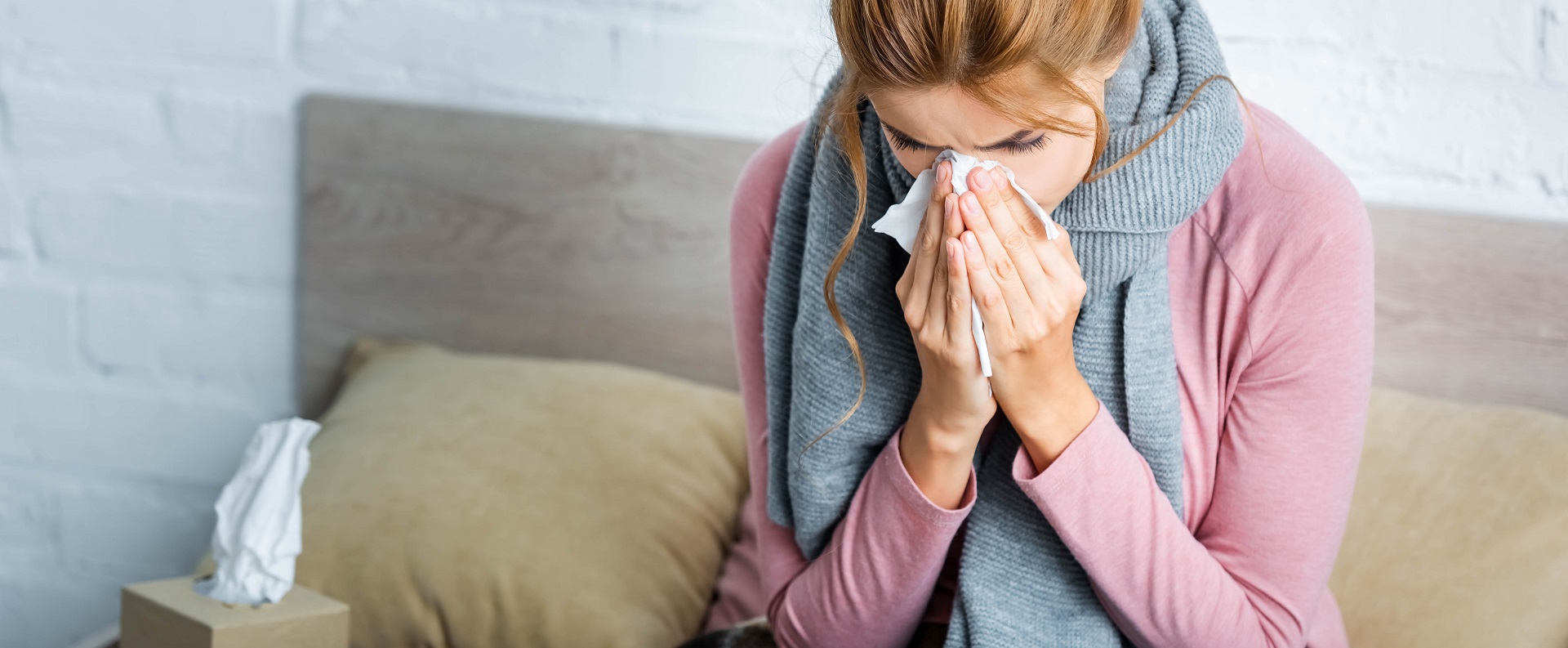 Woman ill from the common cold, blowing her nose with a tissue