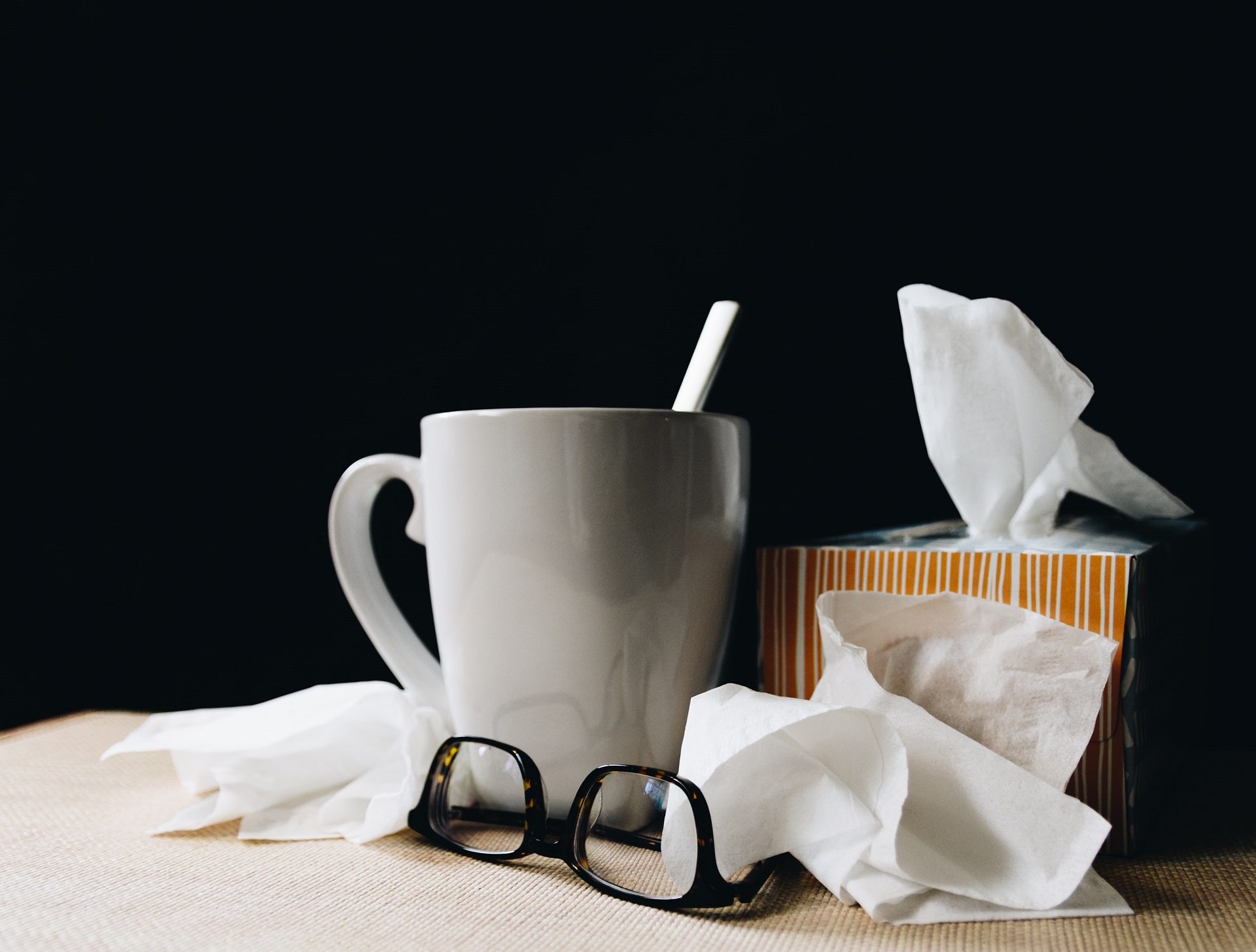 Cup of tea, glasses and box of tissues on the table