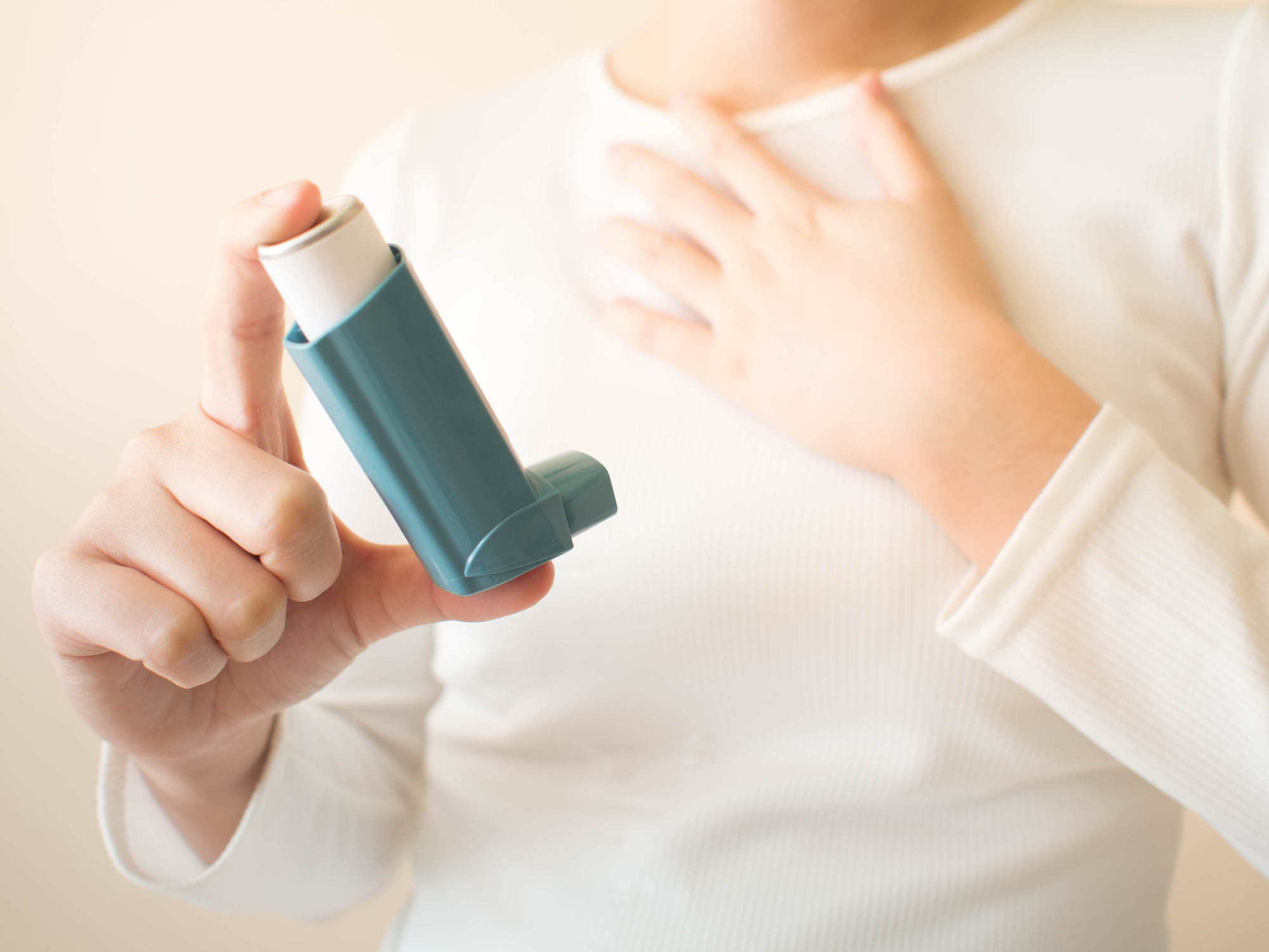 Person holding an inhaler for asthma treatment.